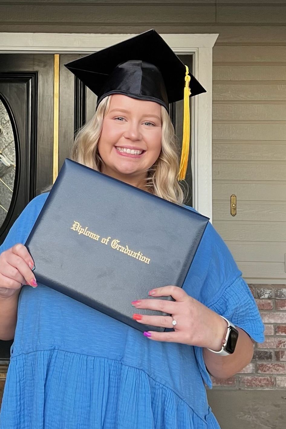 A woman in a graduation cap and gown is holding a diploma.