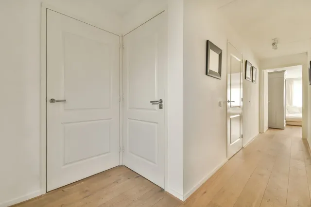 A hallway with white doors and wooden floors in a house.