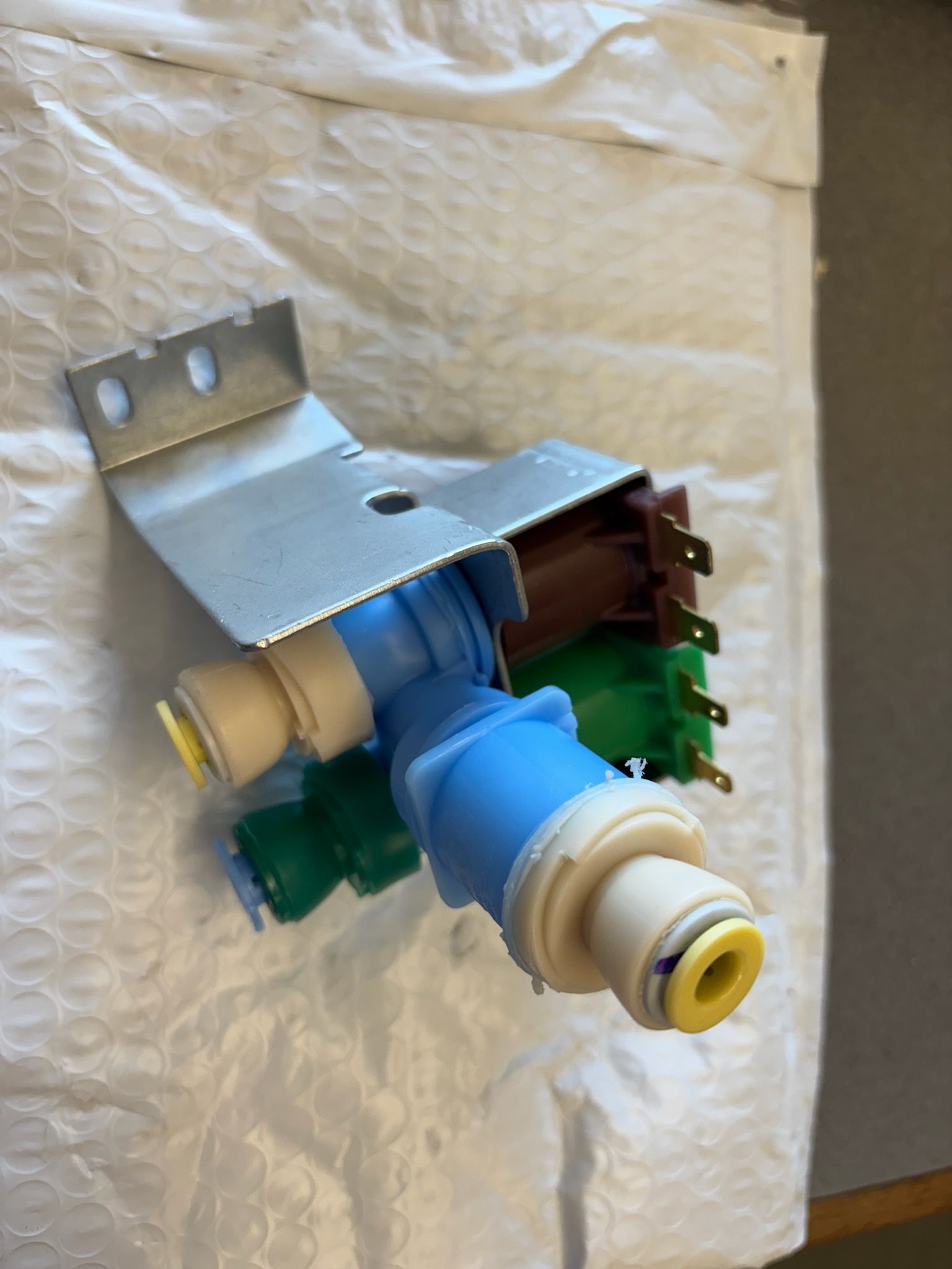 Water valve assembly with blue, green, brown plastic components, metal bracket, on white surface.