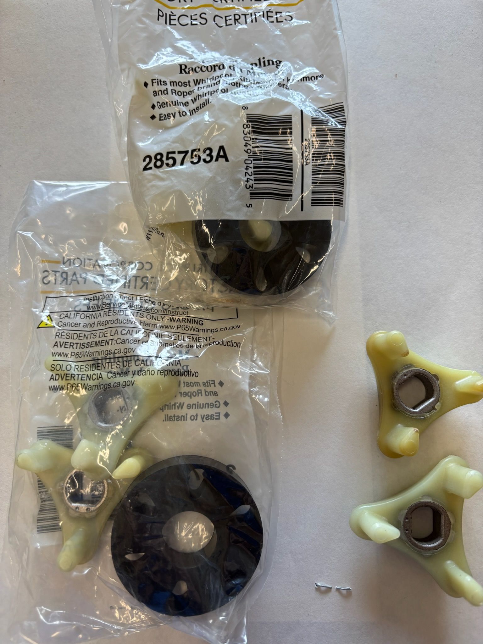 Two packages of appliance parts with black and off-white components, and two loose off-white parts with metal inserts.