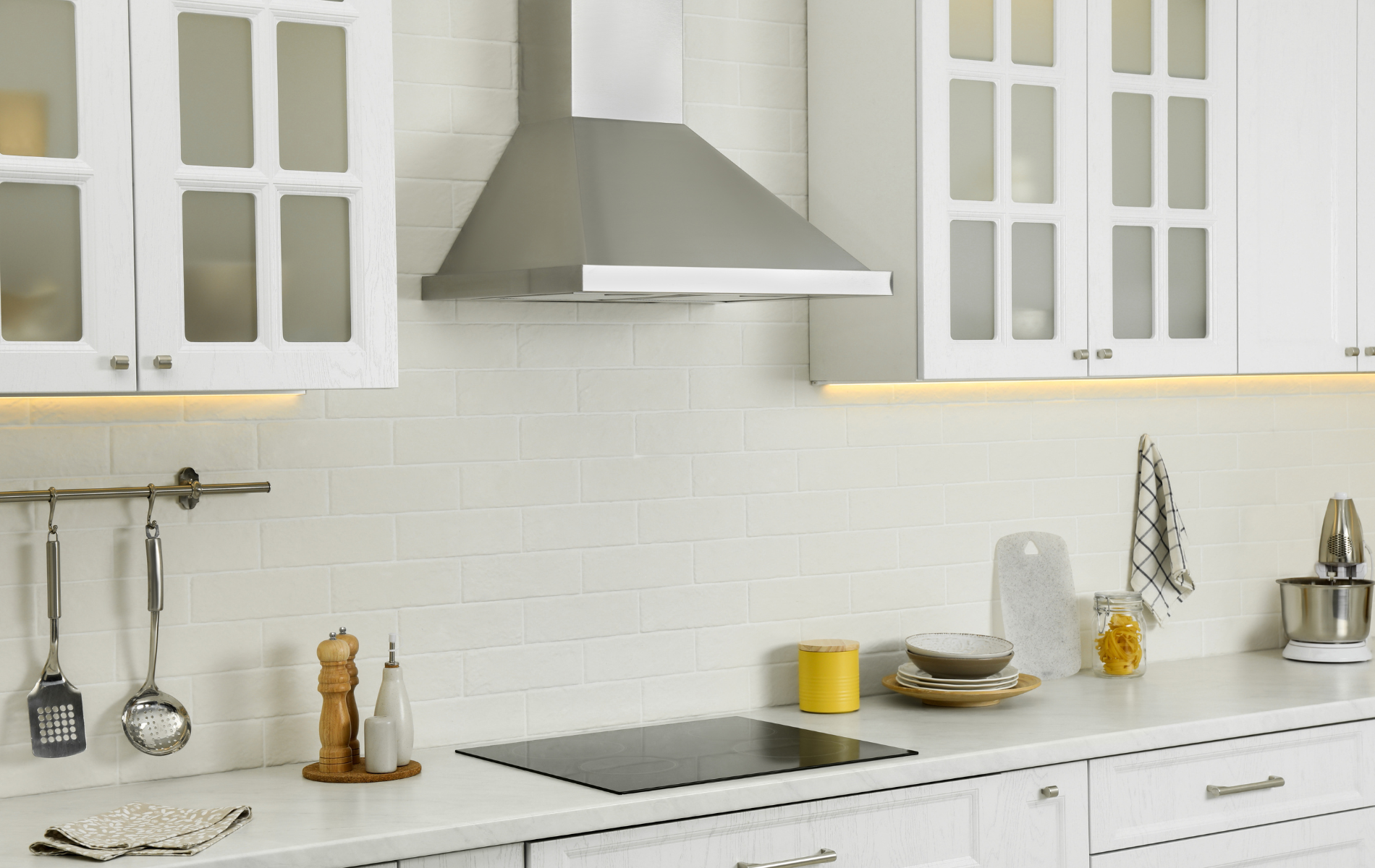 A kitchen with white cabinets and a stove top oven.