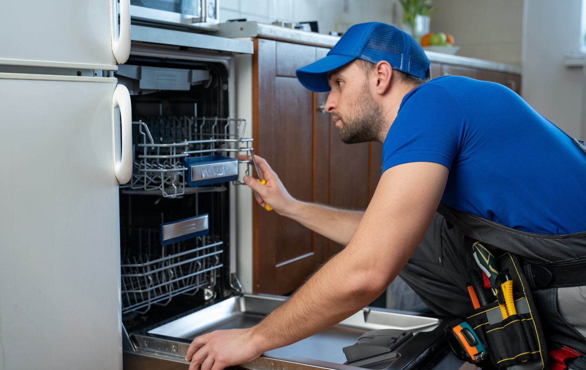 A man is fixing a dishwasher in a kitchen.