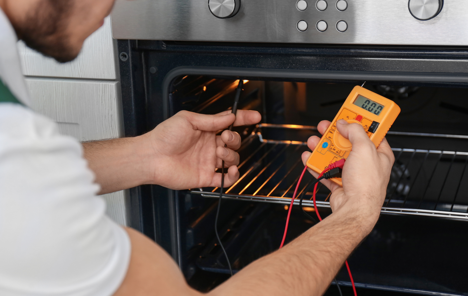 A man is using a multimeter to check the temperature of an oven.