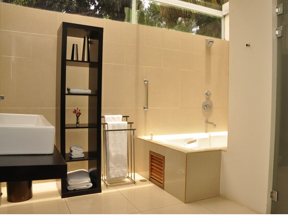 Un baño moderno con lavabo sobre encimera, estantería alta, toallero y bañera empotrada revestida de azulejos.