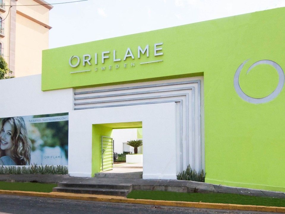 Fachada moderna de Oriflame Suecia con exterior verde lima, detalles arquitectónicos blancos y un gran logotipo.