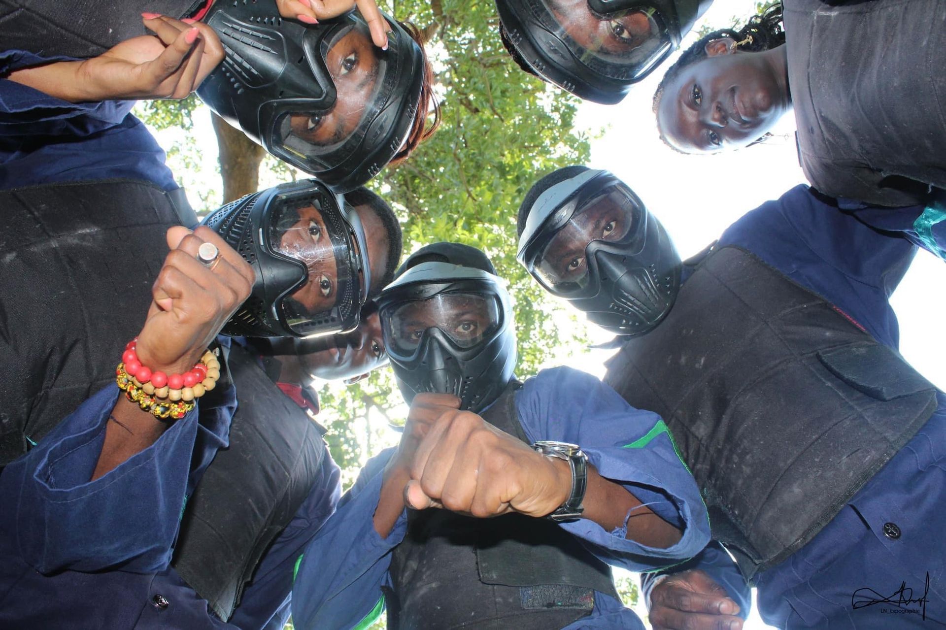 Les joueurs de paintball se regroupent, le regard baissé. Ils portent des masques et des vêtements de protection.