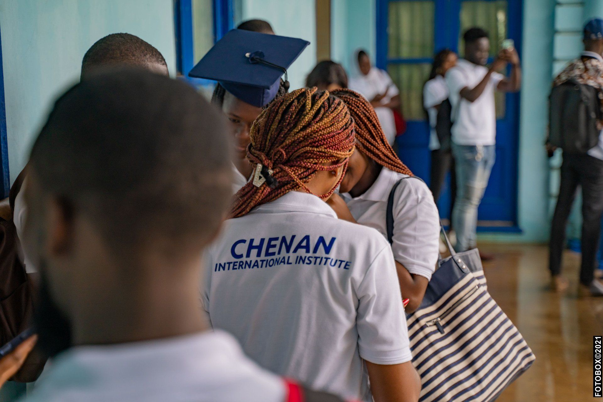 Un groupe d'apprenants de Chenan Africa  personnes portant des casquettes et des chemises de fin d'études se tiennent dans un couloir.