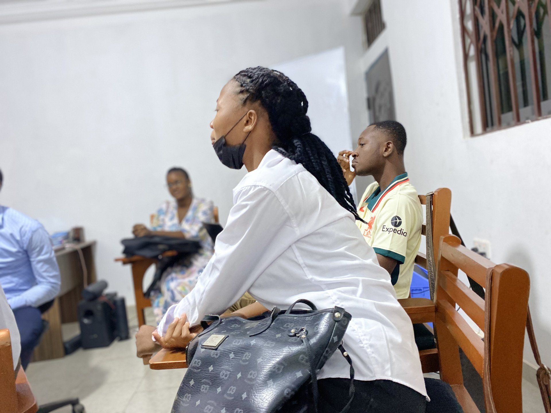 Une apprenante de Chenan Africa portant un masque est assise dans une salle de classe avec d'autres personnes.