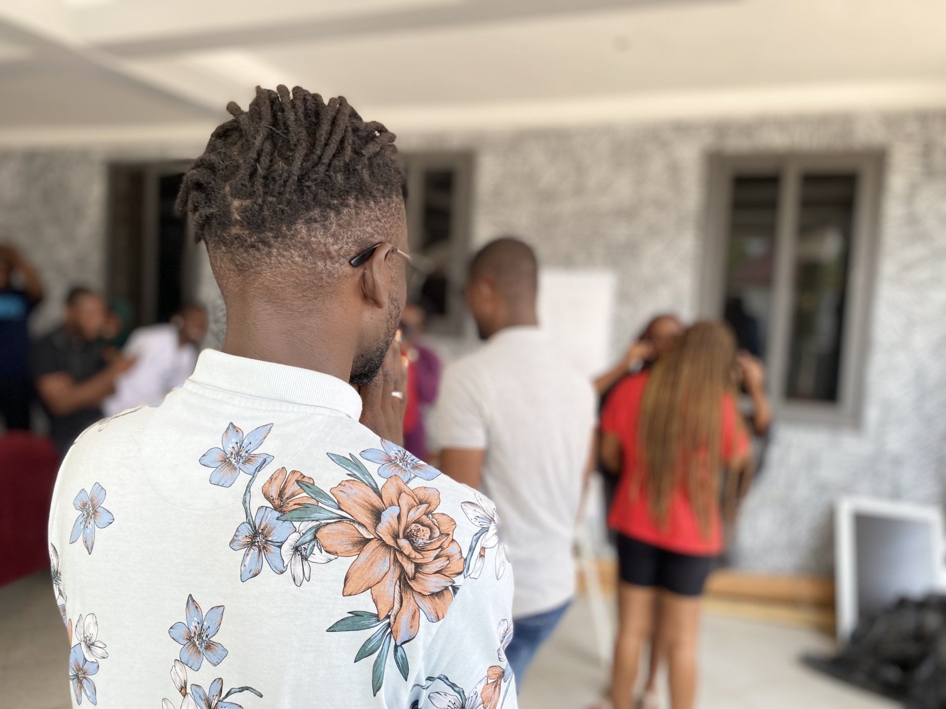 Un homme en chemise à fleurs se tient devant un groupe de personnes.