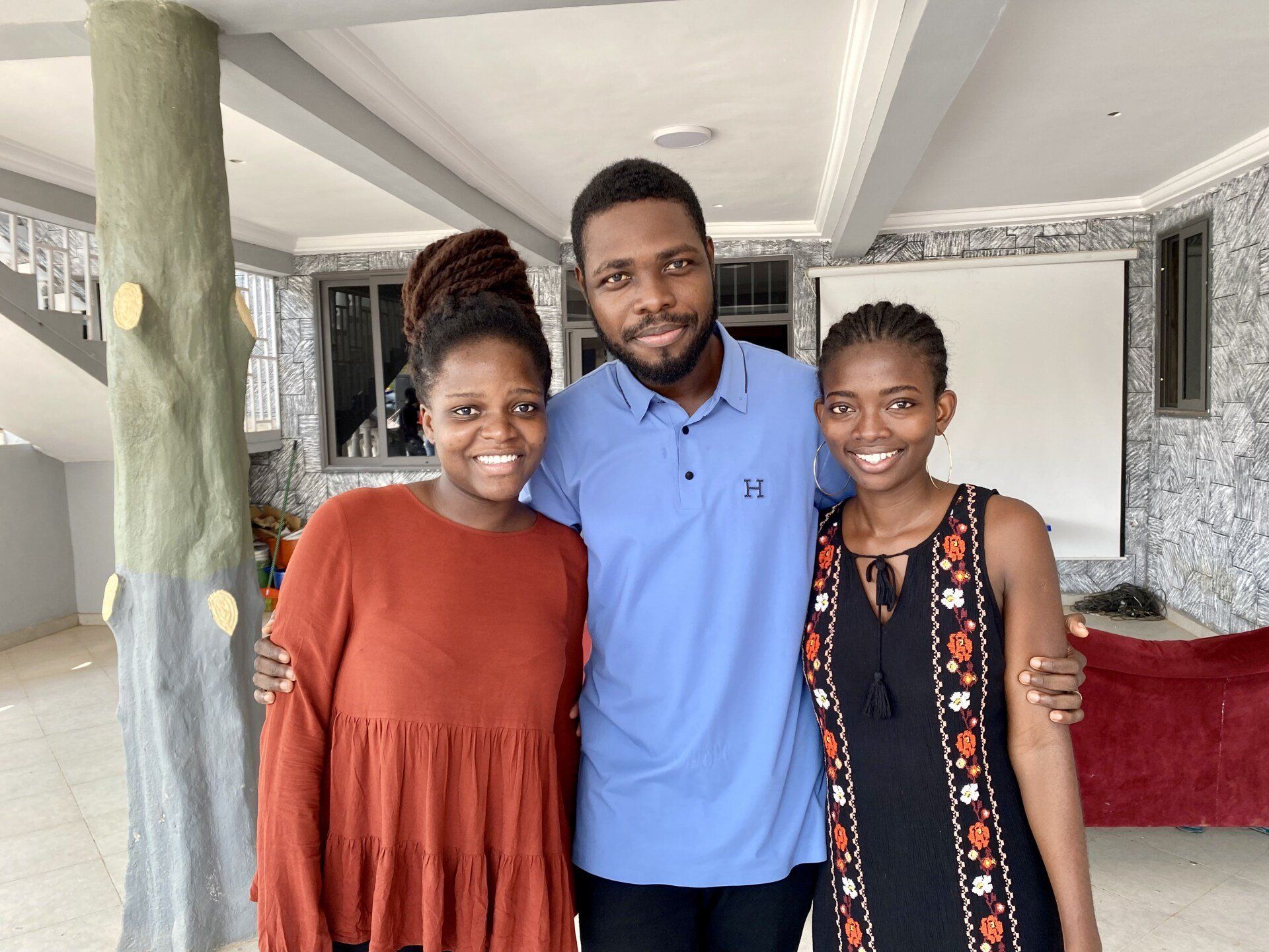 Un homme et deux femmes posent pour une photo dans une pièce.