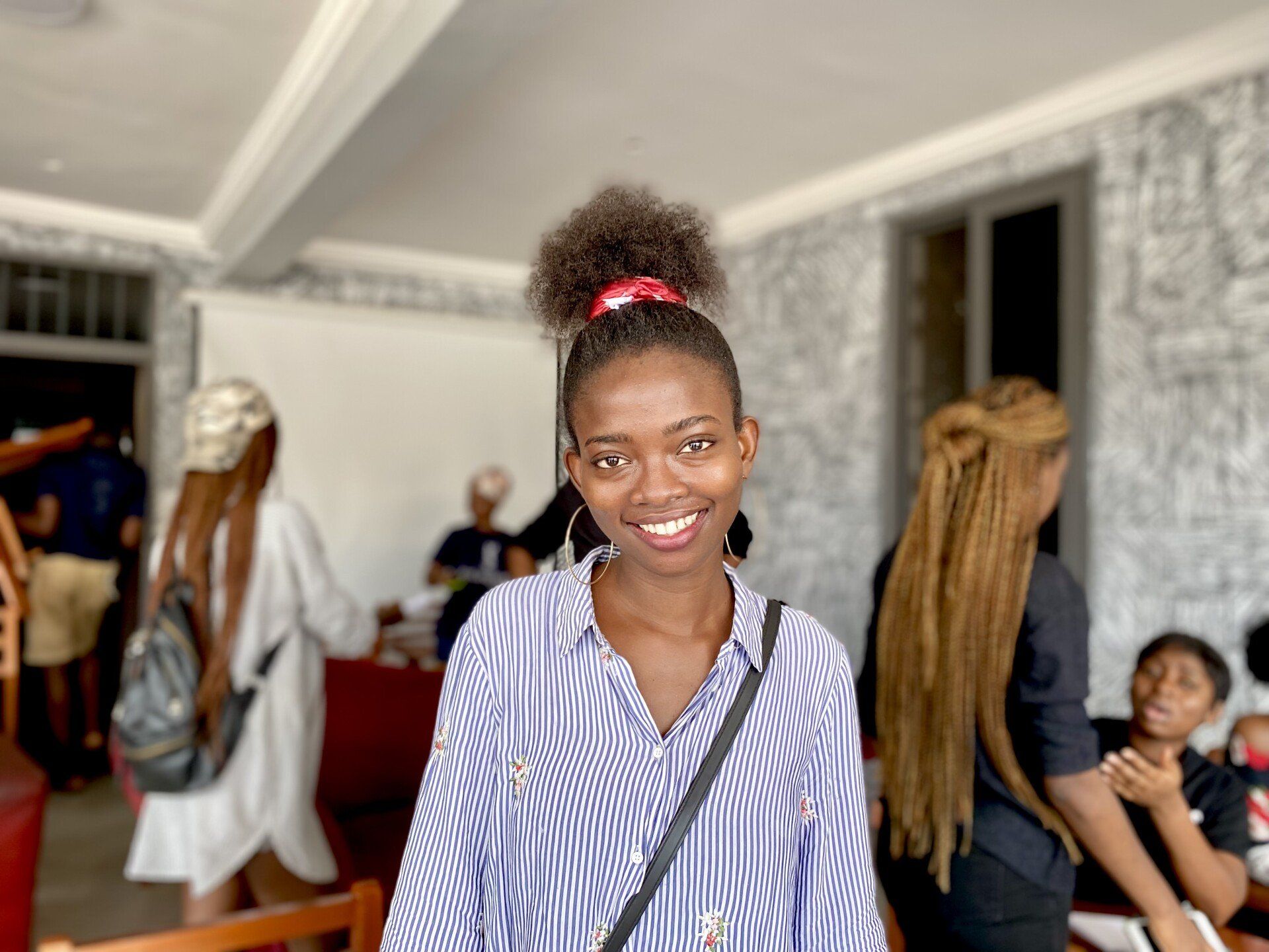 Une apprenante de Chenan Africa en chemise rayée sourit devant un groupe de personnes.