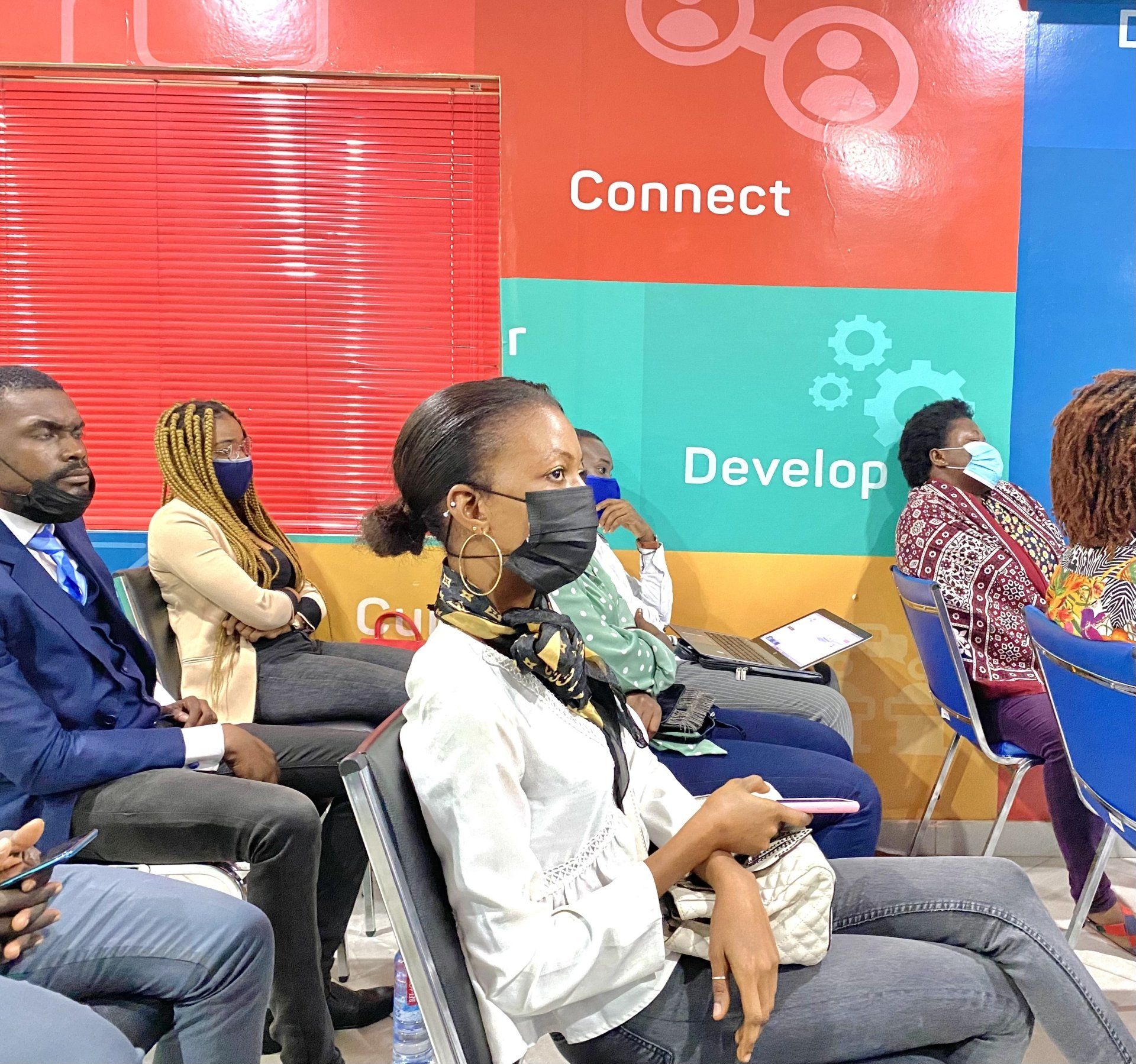 Un groupe de personnes est assise sur des chaises devant un mur qui dit connecter développer