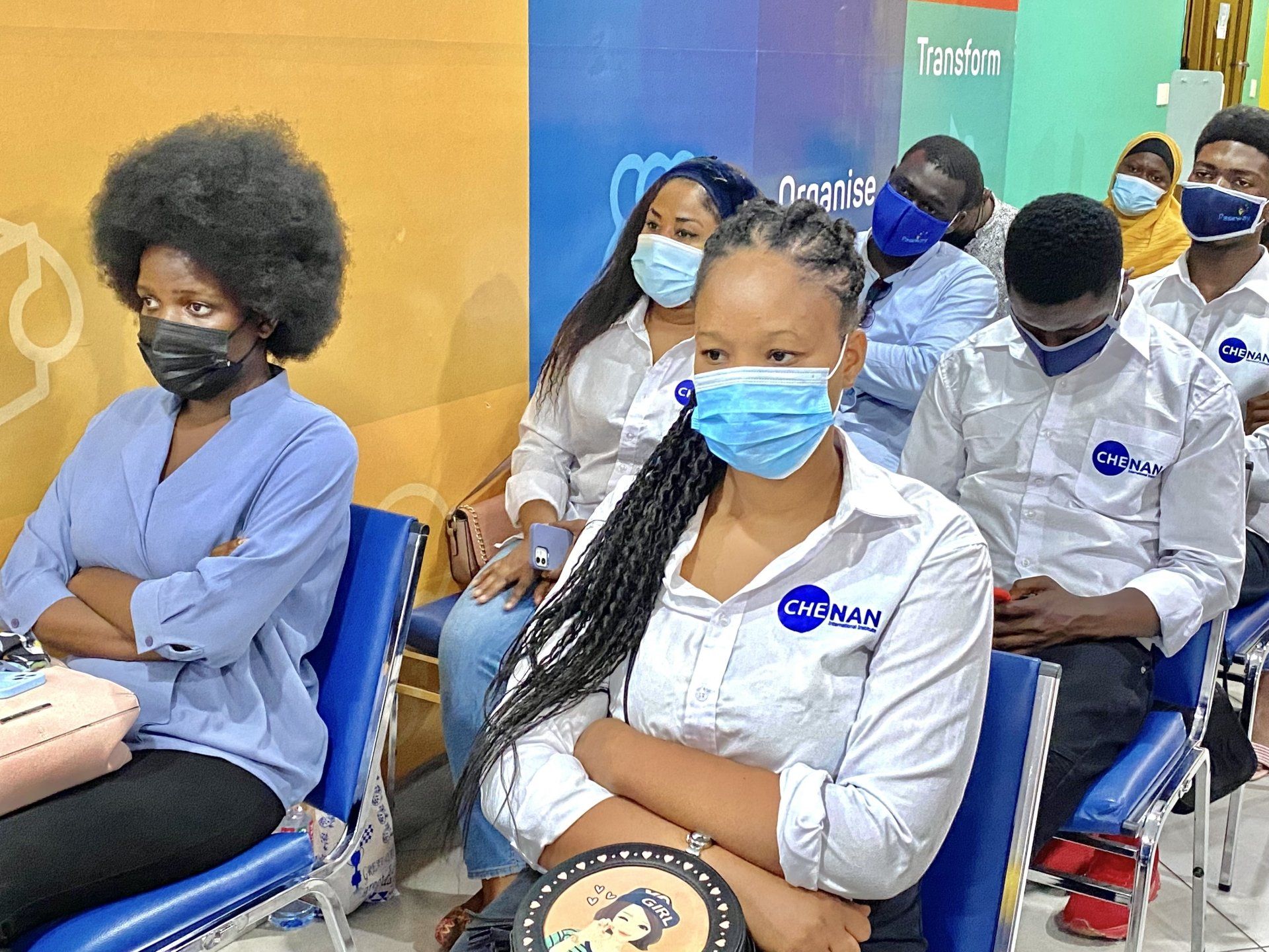 Un groupe de personnes portant des masques sont assises sur des chaises.