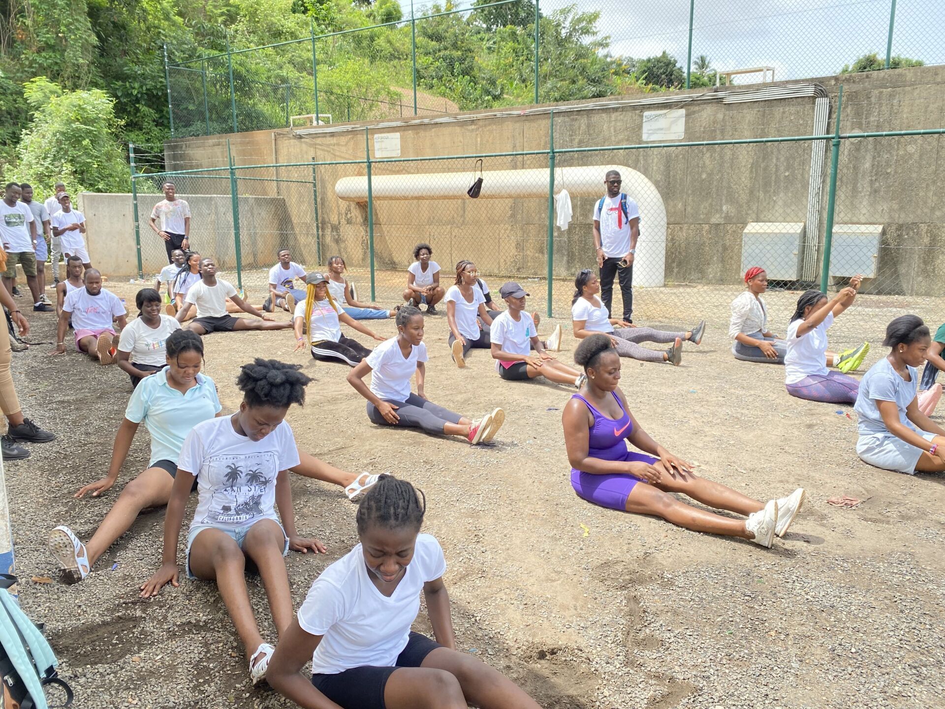 Un groupe de personnes sont assises par terre et se dégourdissent les jambes.