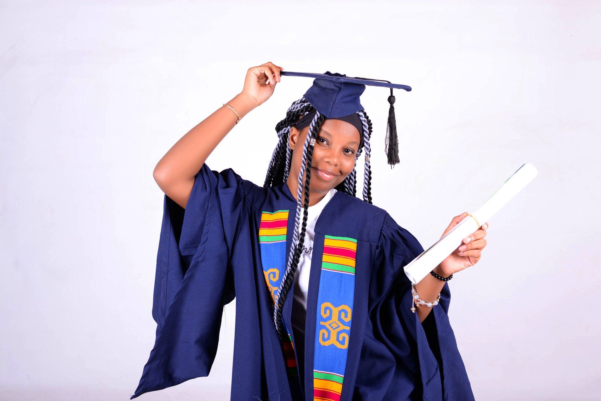 Une femme portant une casquette et une robe de graduation est titulaire d'un diplôme.