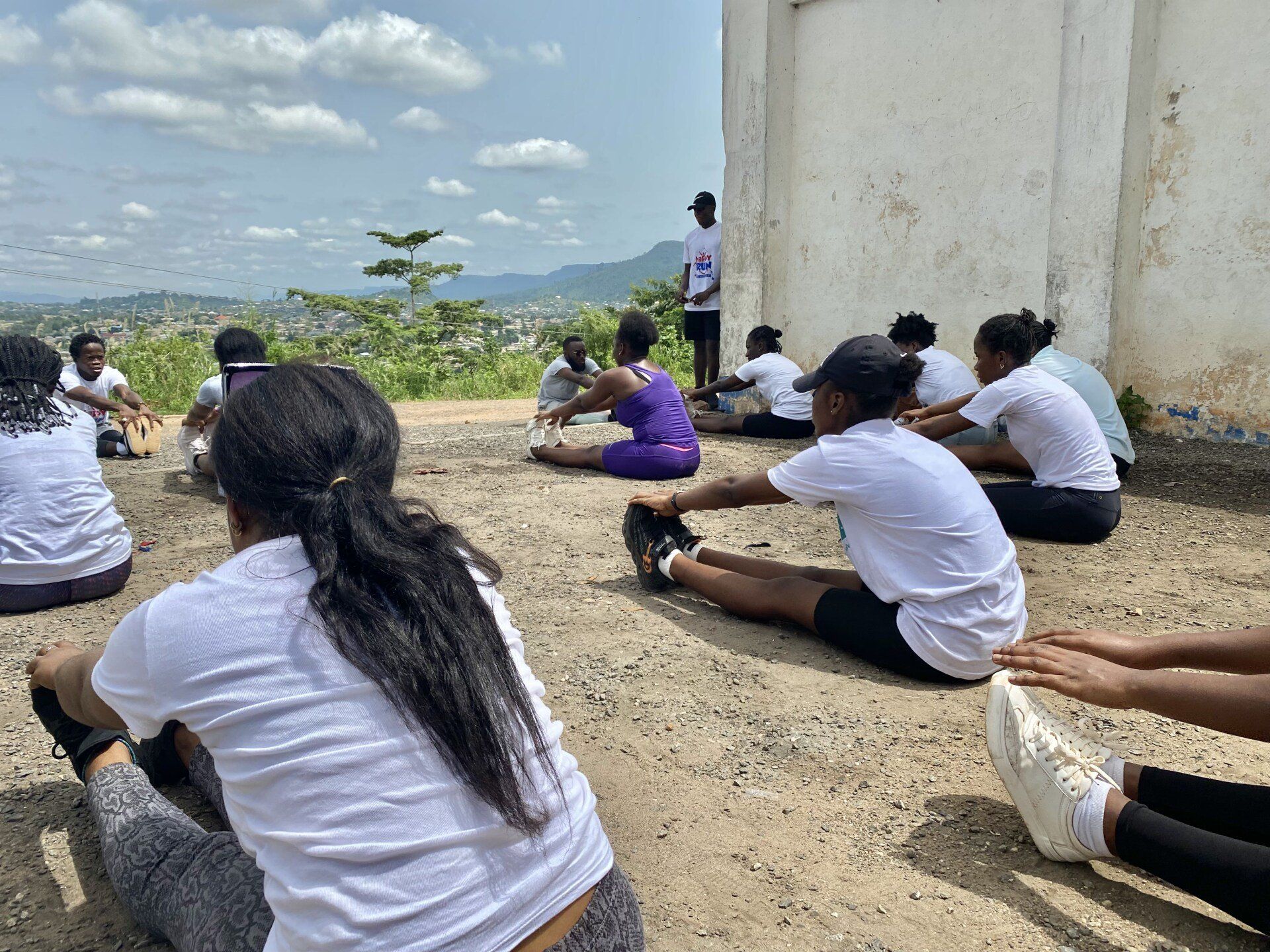 Un groupe de personnes sont assises par terre et se dégourdissent les jambes.