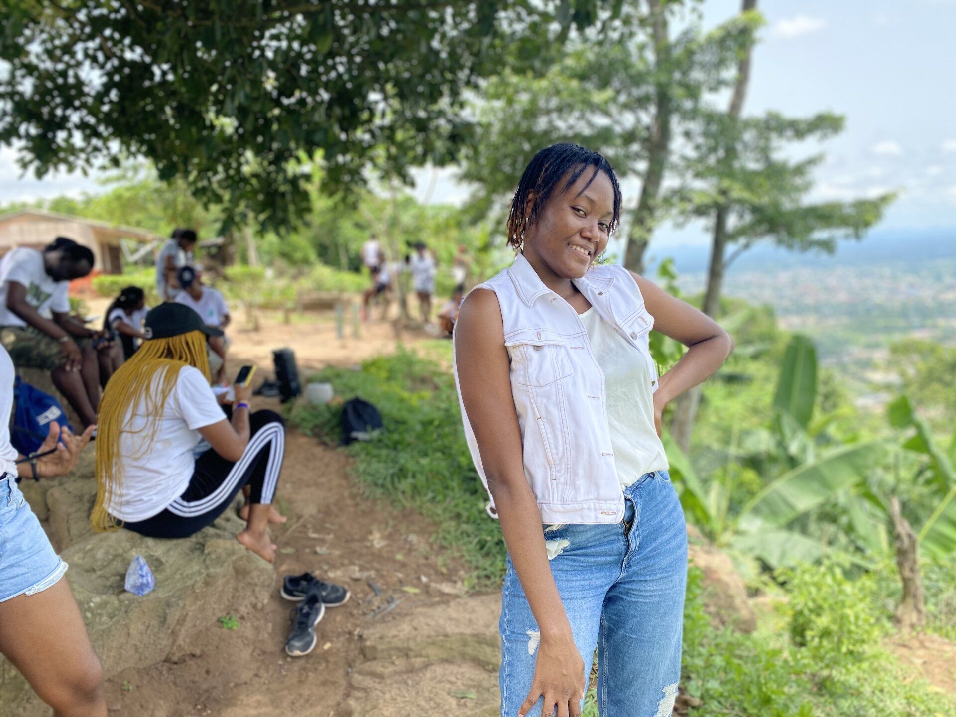 Une femme se tient au sommet d'une colline, les mains sur les hanches.