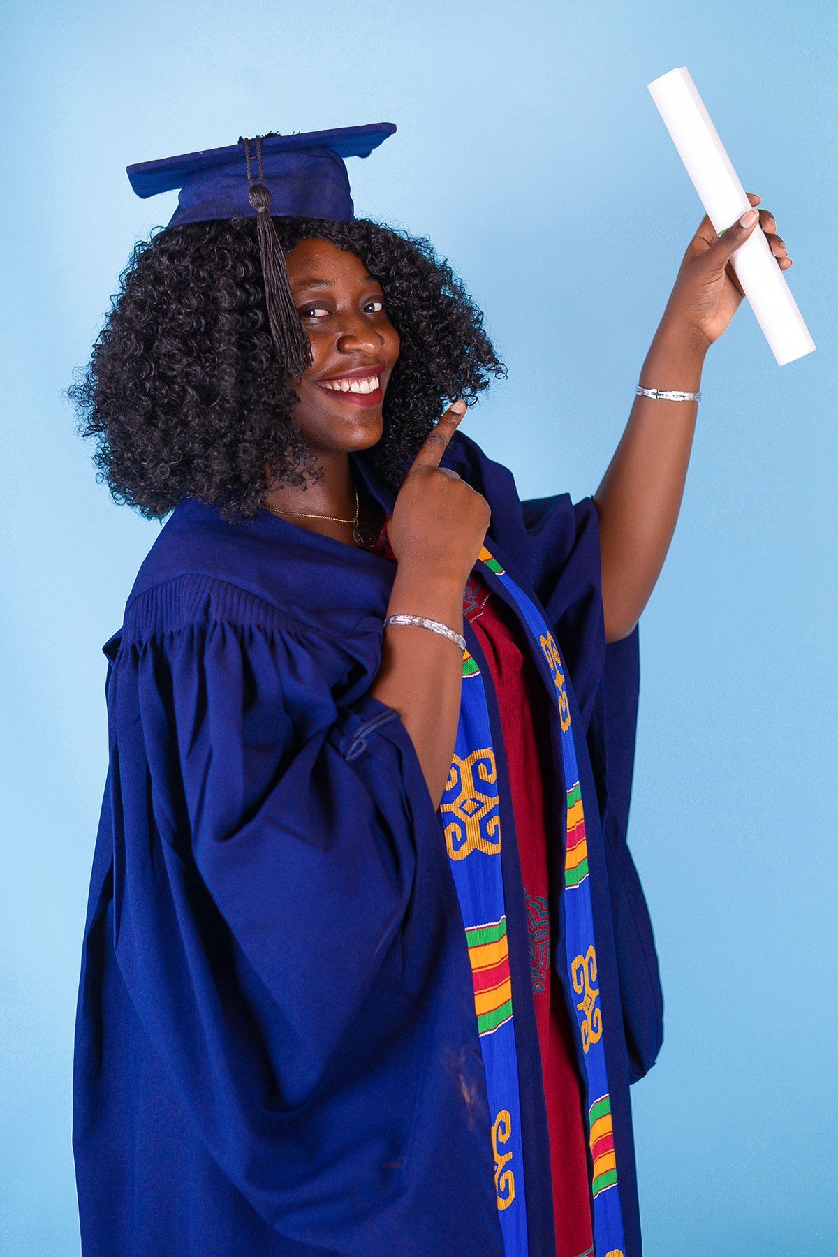 Une femme portant une casquette et une robe de graduation est titulaire d'un diplôme.