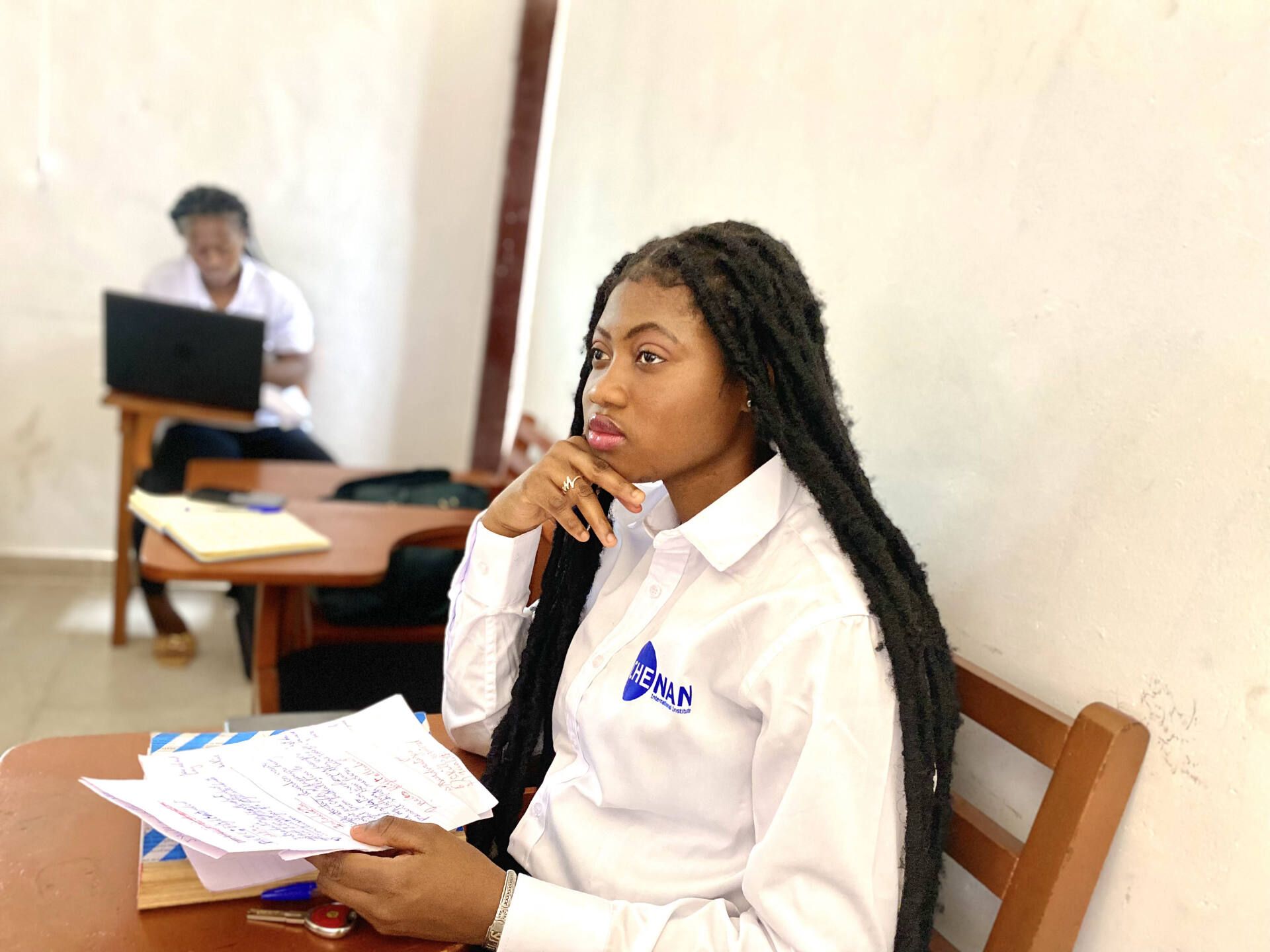 Une apprenante de Chenan Africa est assise à une table avec des papiers à la main.