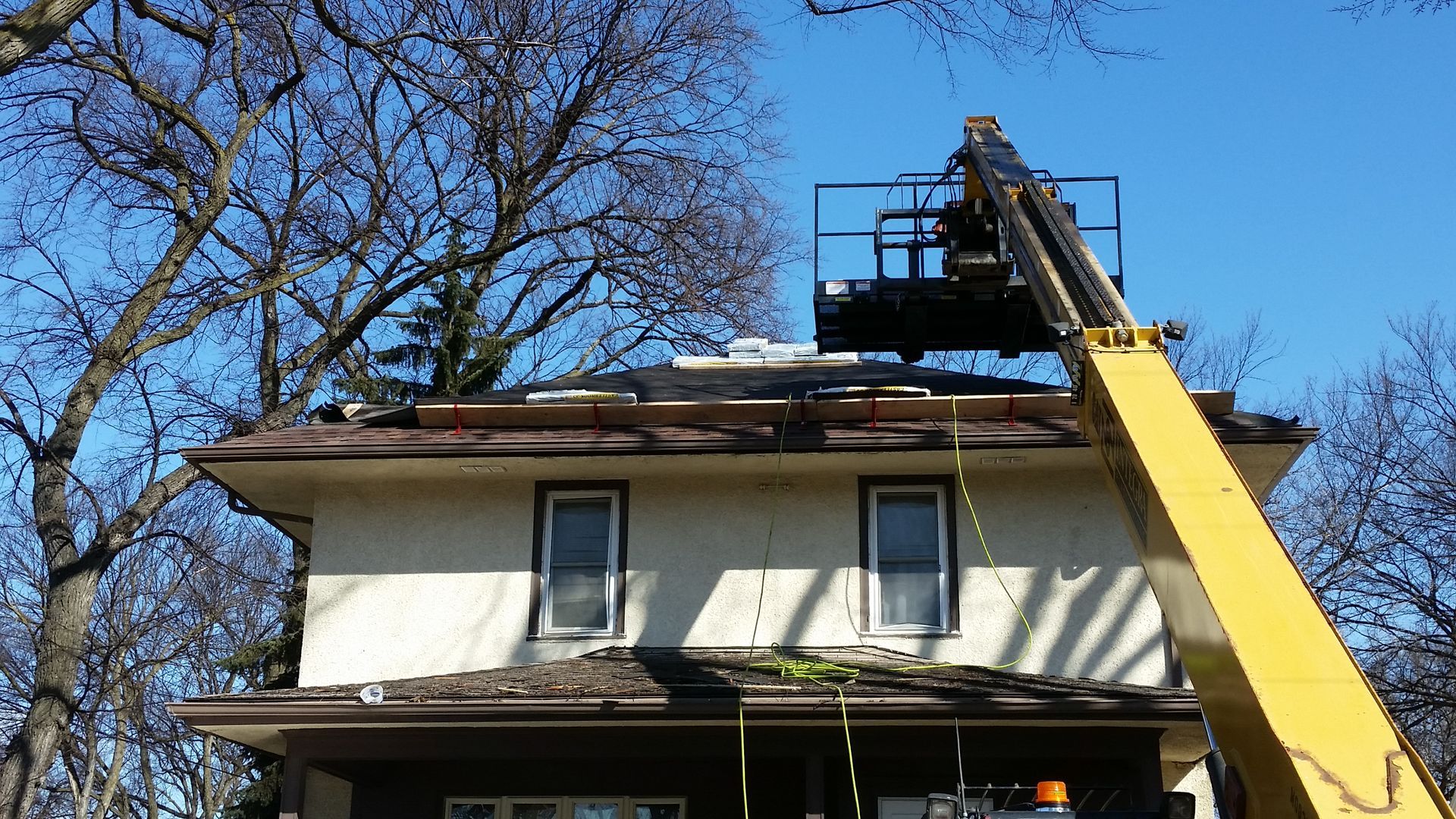 Roof Safety Jacks with Planks and Bundles of new laminate shingles on an old Stucco House near Fargo-ND and Moorhead-MN