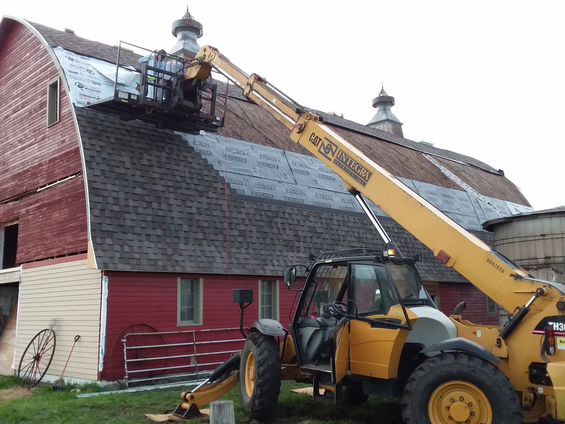 Laminate Shingles being installed on a curved barn using a Telehandler near Fargo-ND and Moorhead-MN