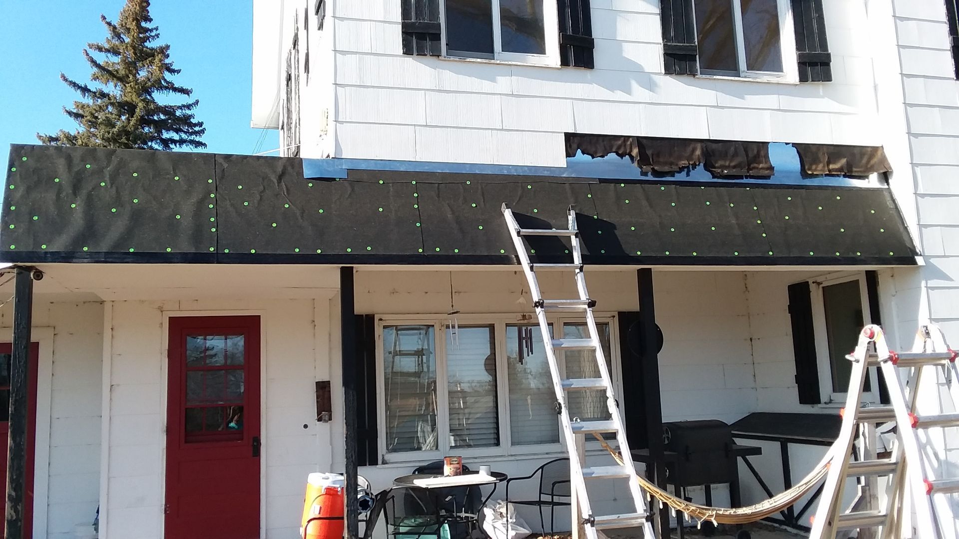 Porch Roof with White Siding Removed to Install New Roof to Wall Flashing in Grandin, ND