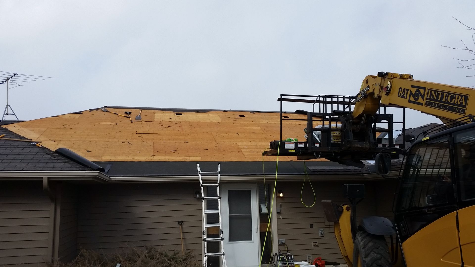 Front of House with Half Exposed Roof Decking and a Telehandler near Finley ND