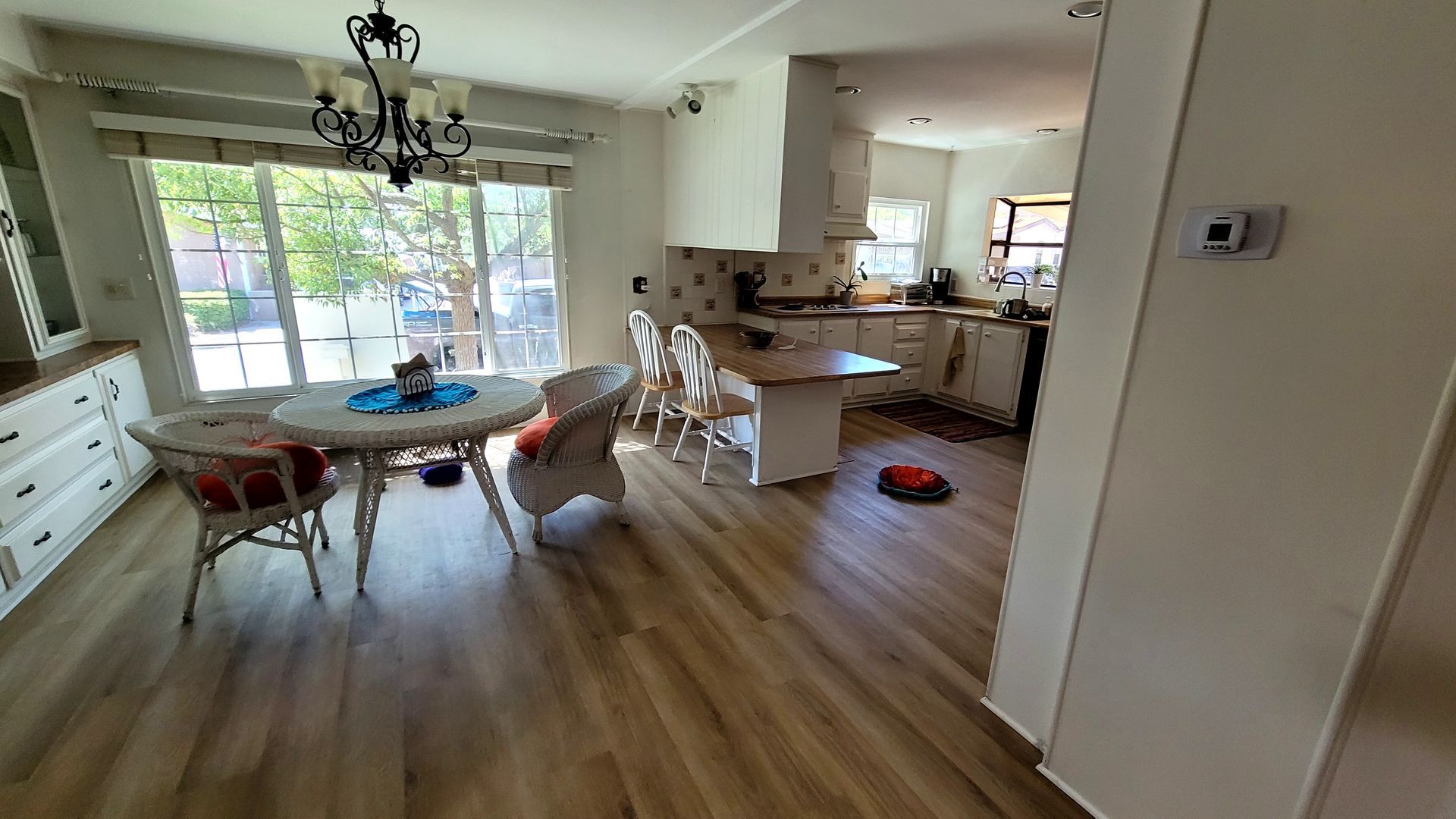 A bright, open-concept dining area and kitchen with wood-look flooring, a round white table, and a white kitchen island.