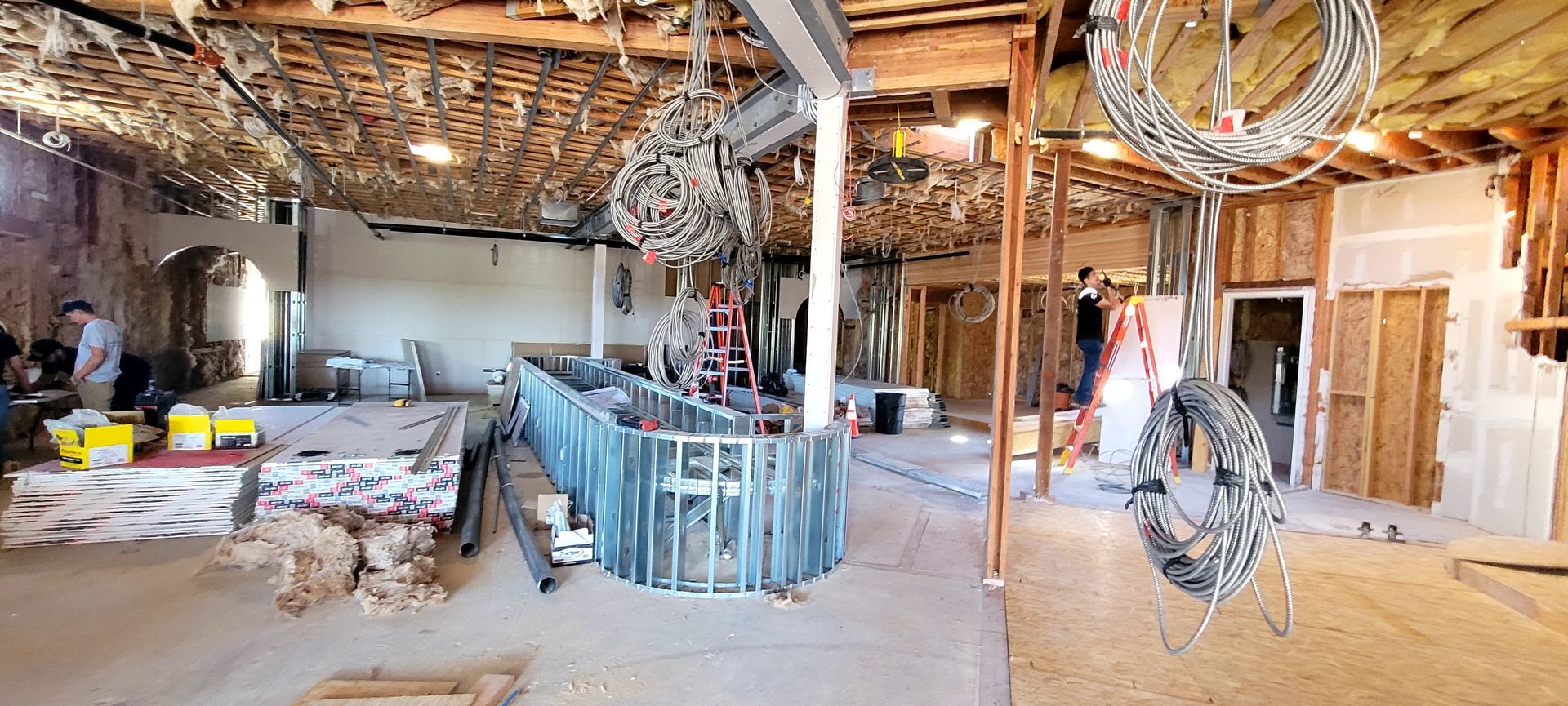 Construction site with a metal bar frame, exposed ceiling, and tools in a large, open interior space.