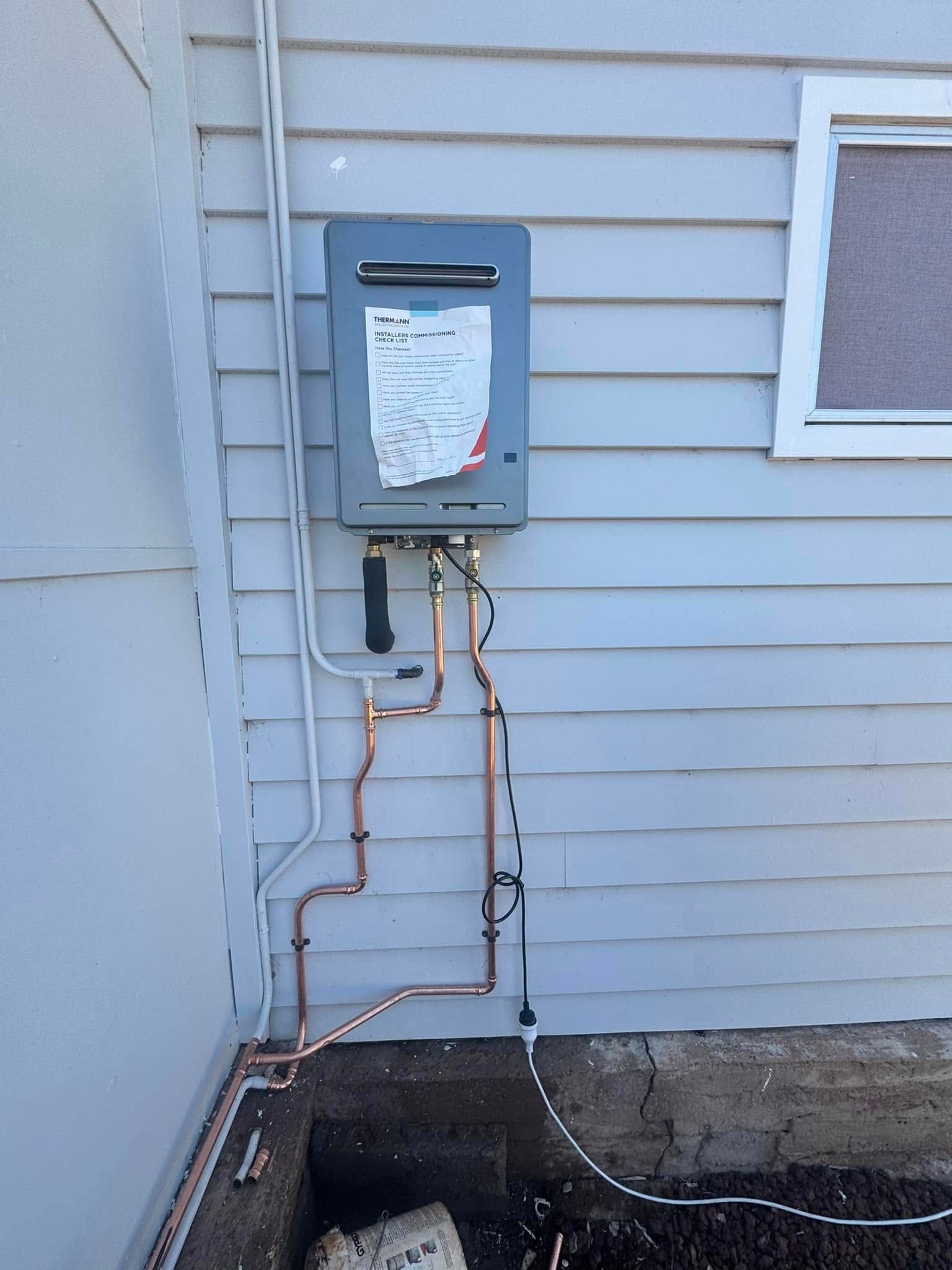 Gas Water Heater Mounted On Light Blue House Siding With Copper Pipes — BJG Plumbing in Coolamon, NSW
