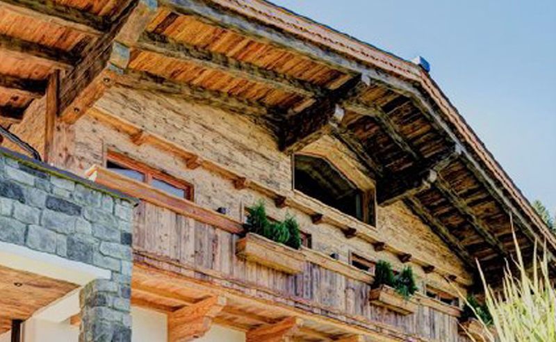 Ein großes Holzhaus mit Balkon und einem blauen Himmel im Hintergrund.