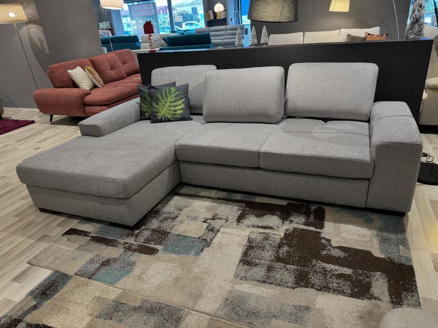 Divano componibile grigio con chaise longue su un tappeto a fantasia in un negozio di mobili.