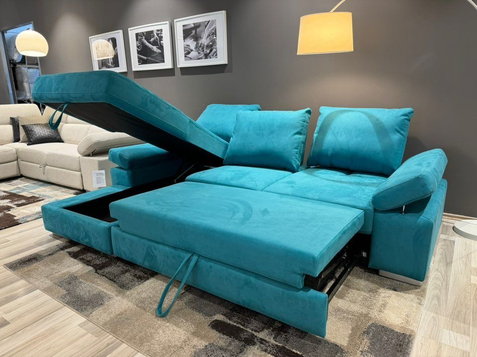 Divano componibile color verde acqua con vani portaoggetti aperti, allestito in uno showroom.