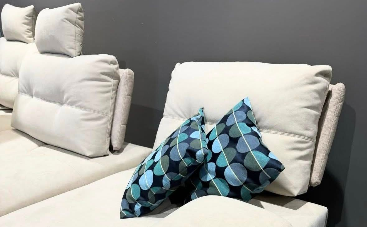 Divano bianco con cuscini a fantasia blu contro una parete grigia.