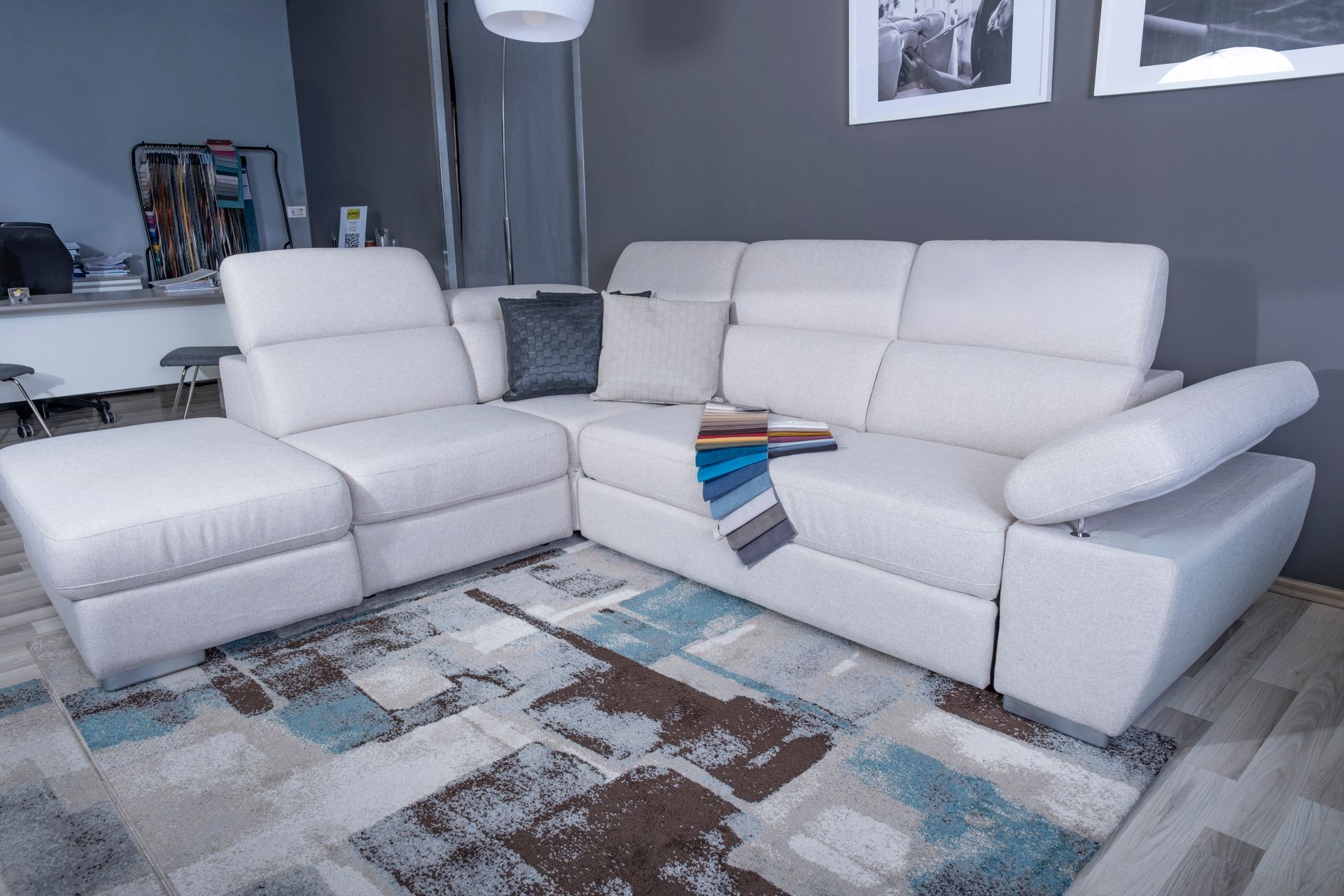 Divano componibile bianco su un tappeto a fantasia in una stanza con una parete grigia.