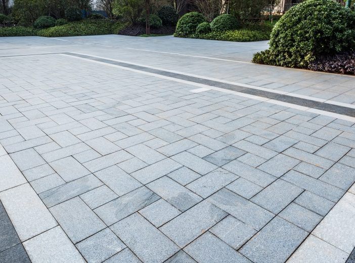 A brick driveway with a drain in the middle of it.