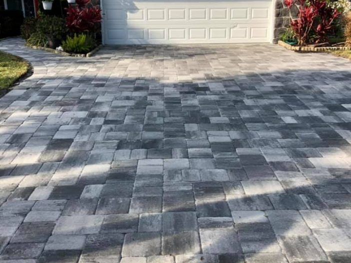 A brick driveway with a garage door in the background.