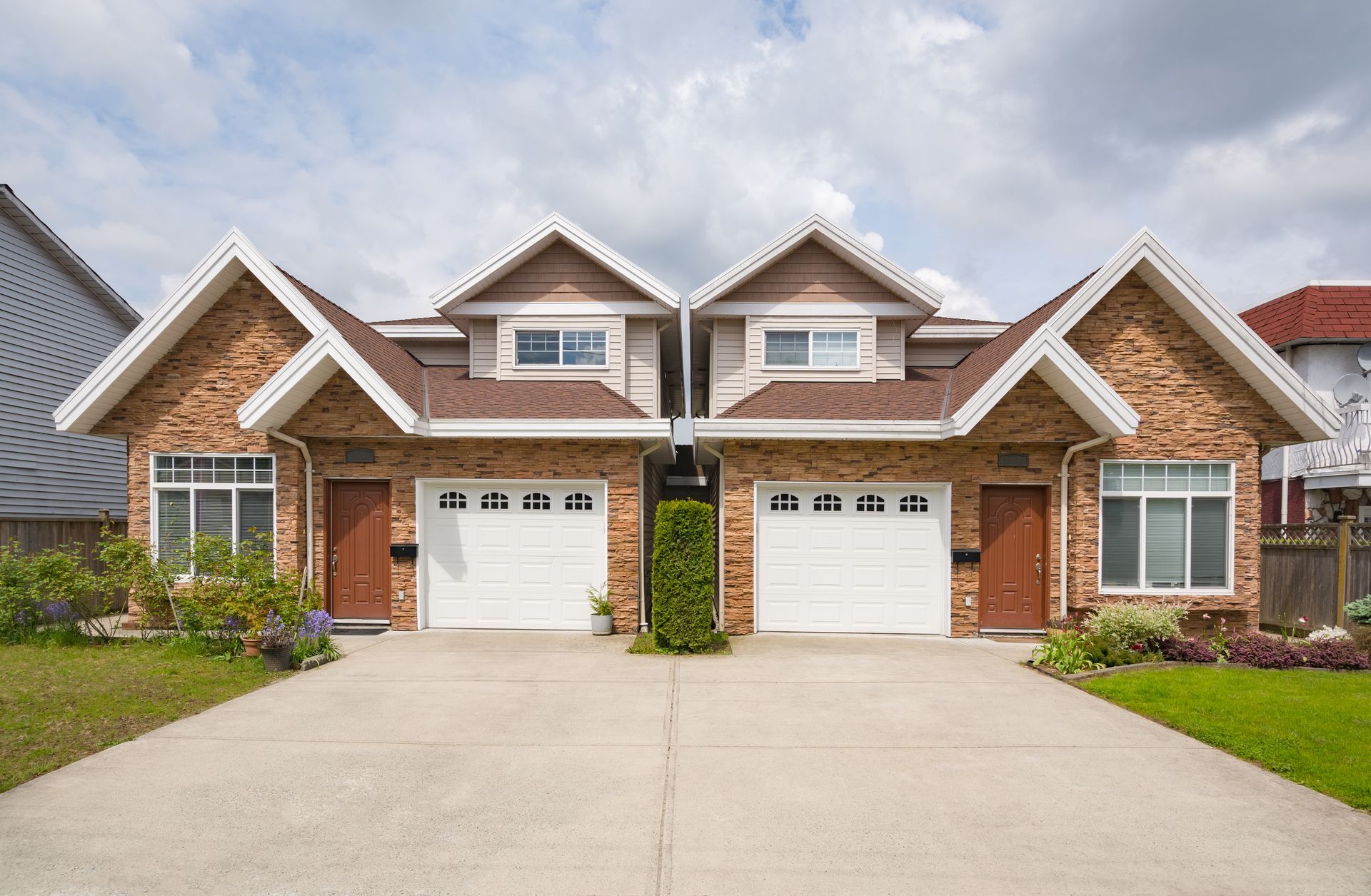 A couple of houses with two garages next to each other.