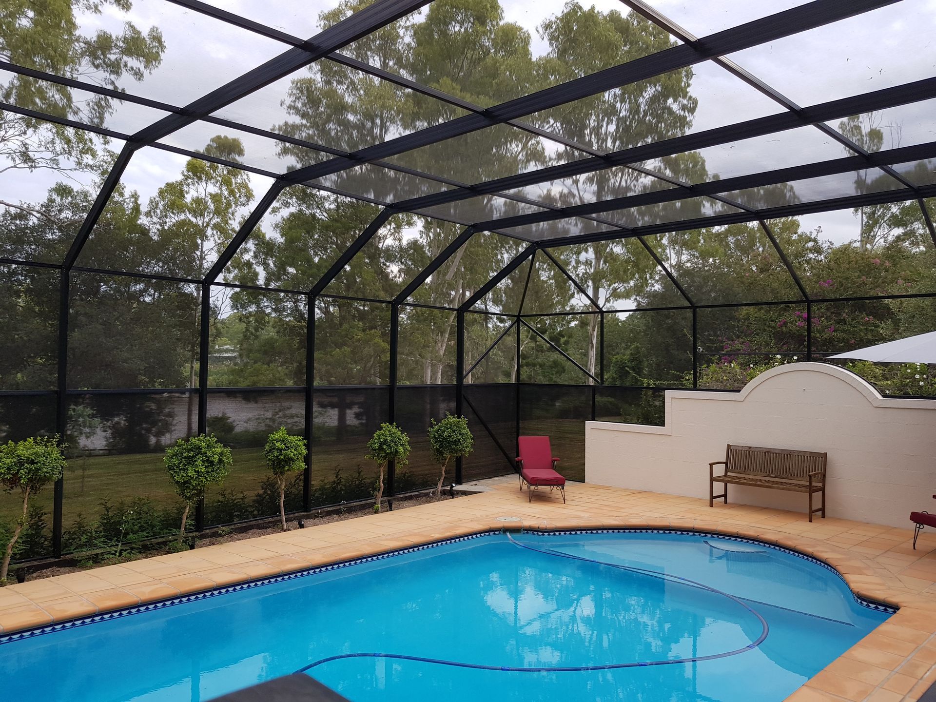 A screened in swimming pool with a bench and chairs