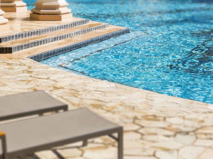 A swimming pool with stairs leading up to it and chairs on the side.