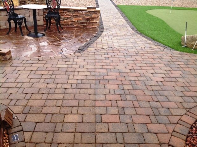 A brick driveway leading to a garage door of a house.