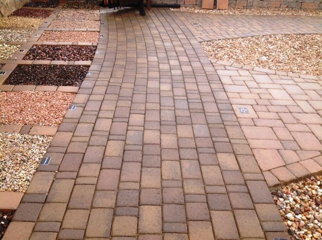 A brick driveway leading to a garage door of a house.