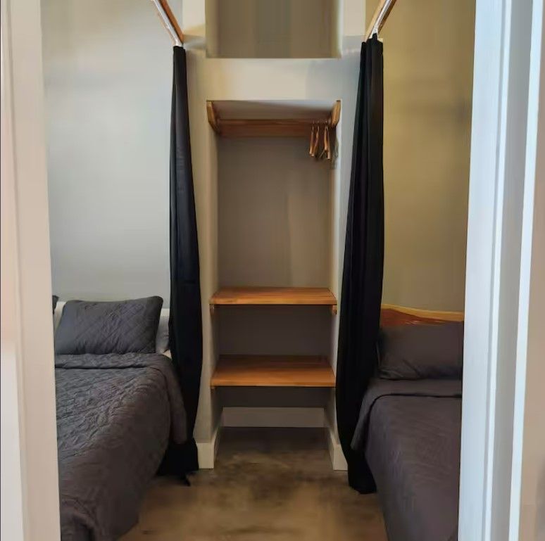 A bedroom with two beds and a closet between them.