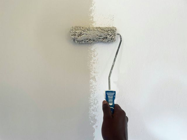 Hand painting a white wall with a paint roller