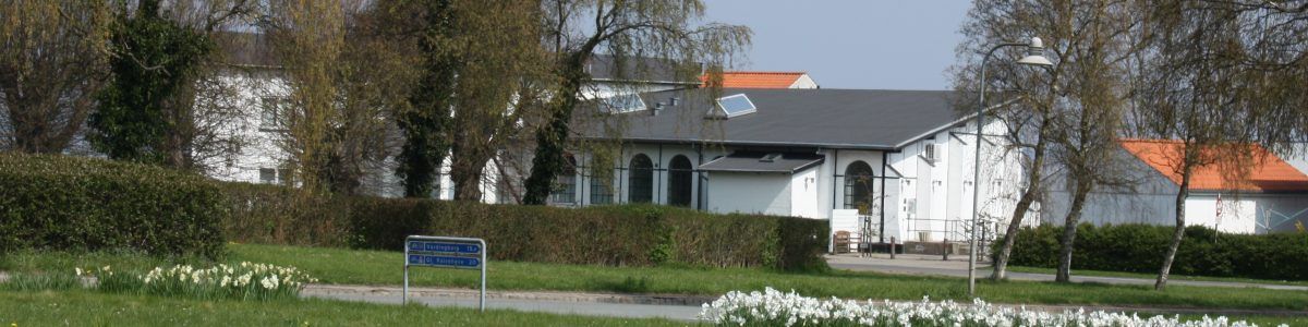 Et hvidt hus er omgivet af træer i en park.