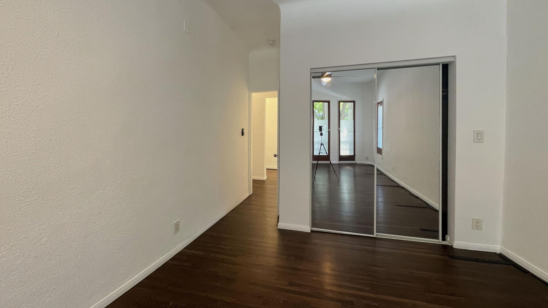 Interior view with dark hardwood floors, white walls, and a sliding door.