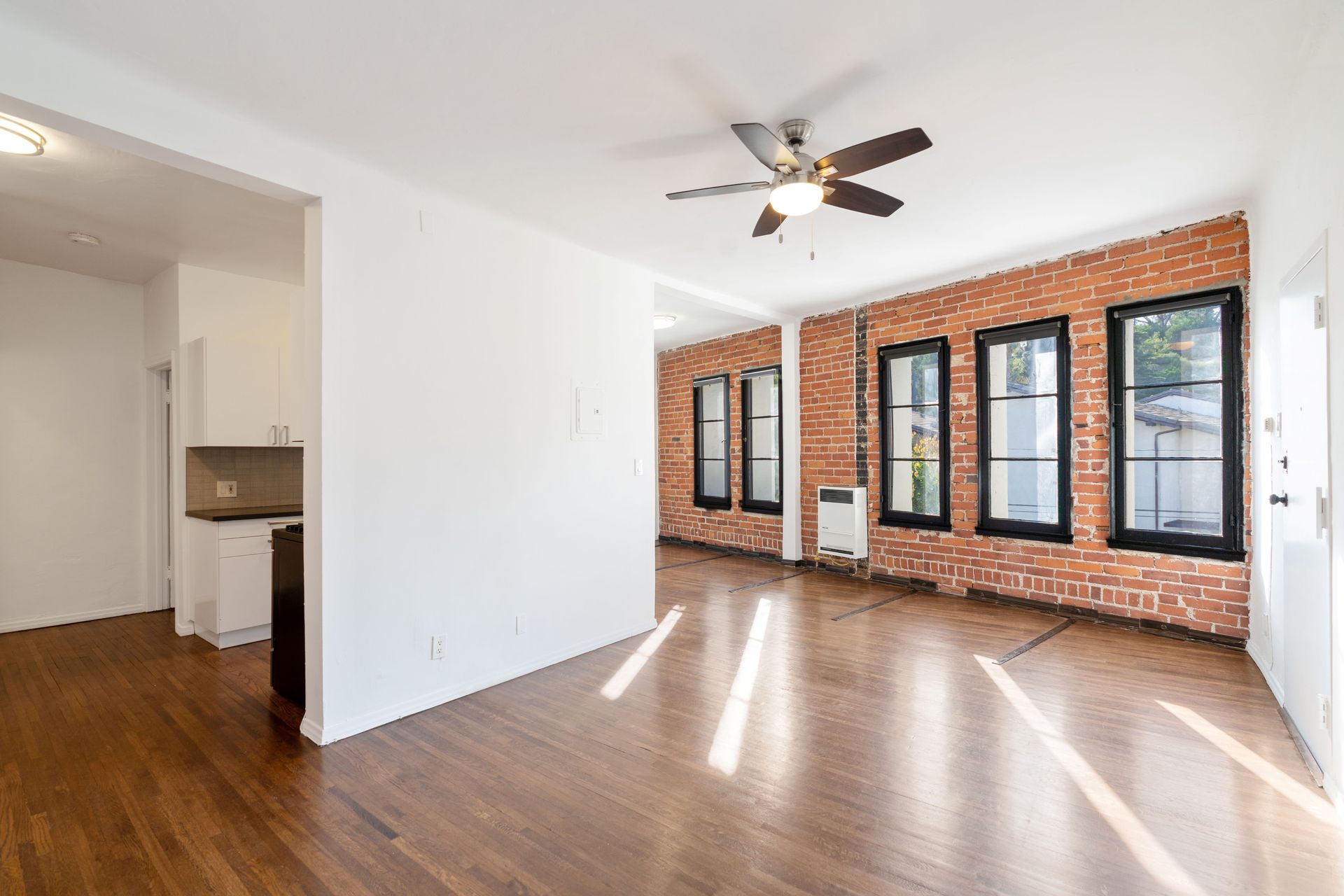 Bright living space with exposed brick wall, hardwood floors, and windows.