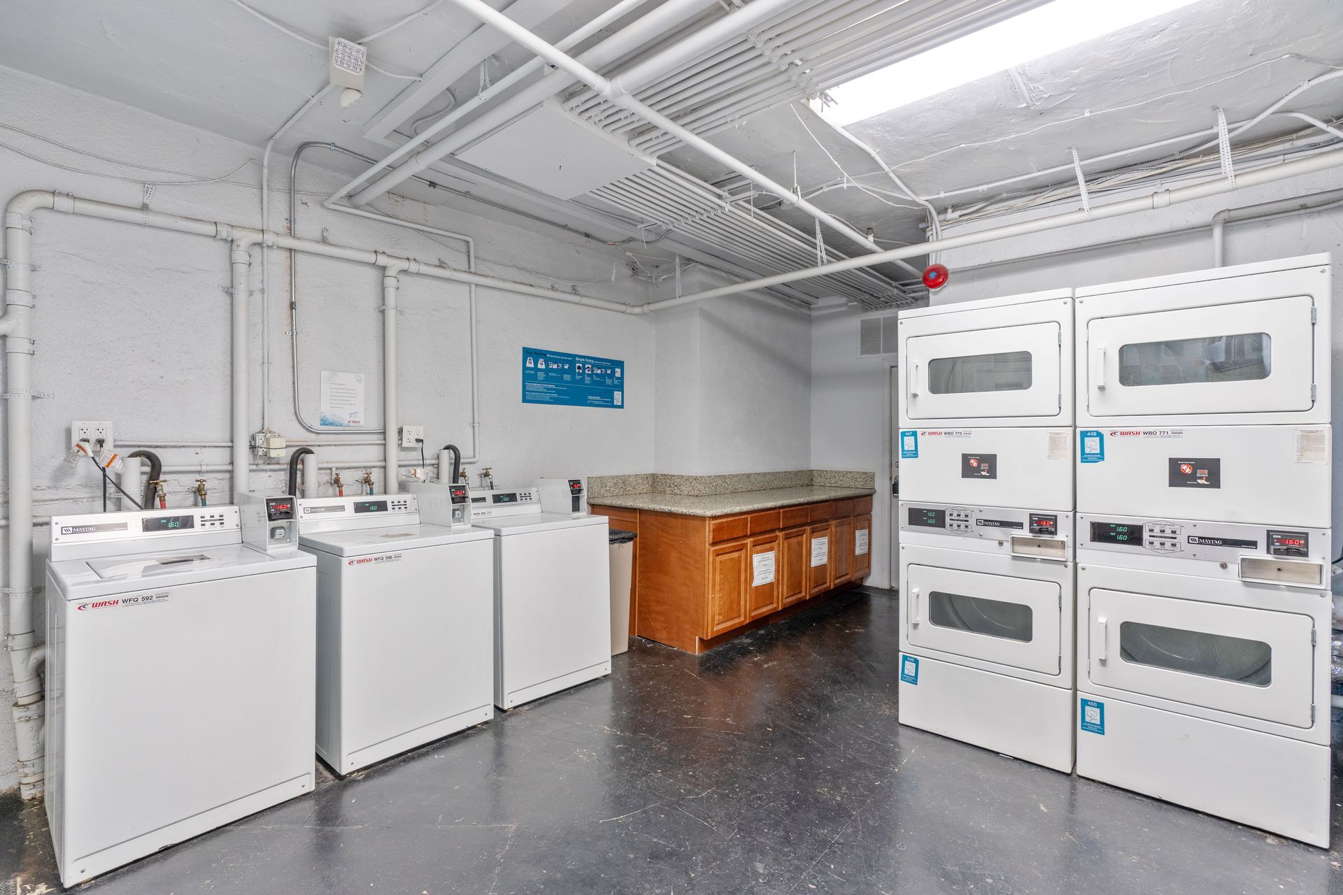 Laundry room with several white washing machines and dryers.