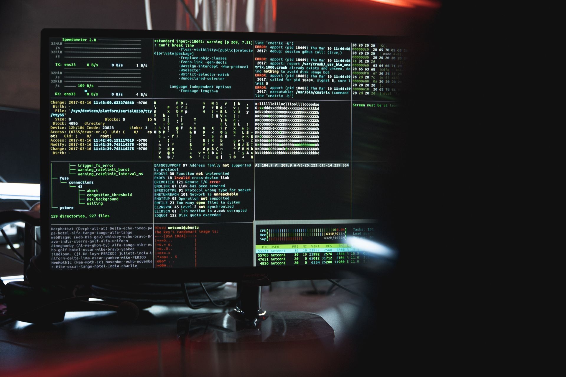 A computer monitor is sitting on a desk in a dark room.