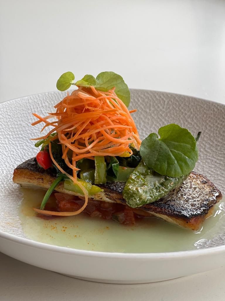 Een wit bord met daarop een stukje vis en groenten.